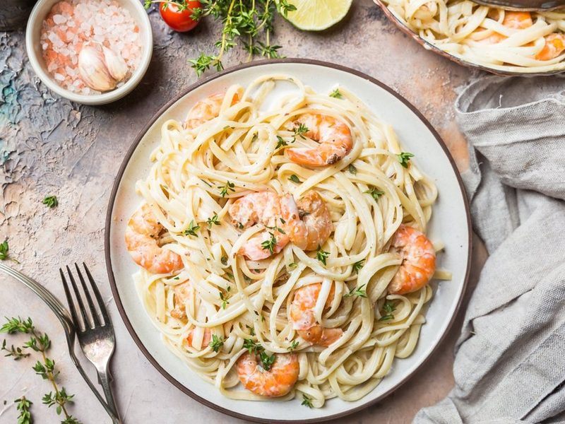 Creamy shrimp fettuccine with fresh thyme on a ceramic plate